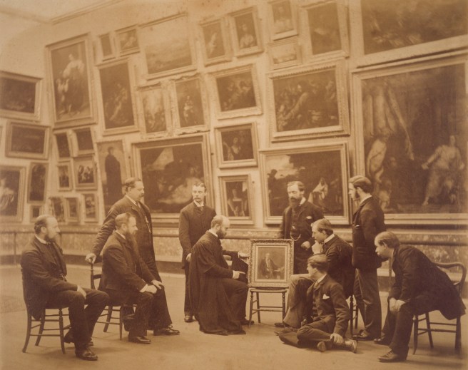 Archive photograph showing staff, Director and Assistant Director (M. R. James, seated right of painting) in Gallery Three at The Fitzwilliam Museum, dated 2nd November 1887. © The Fitzwilliam Museum, Cambridge. Reproduced under license.